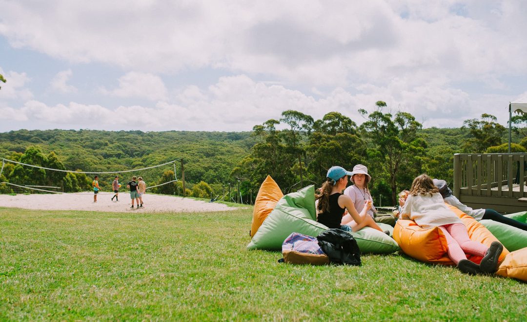 Families sitting on the grass on bean bags overlooking the valleys and adventure actvities on family open day at Golden Valleys Adventure Camp.