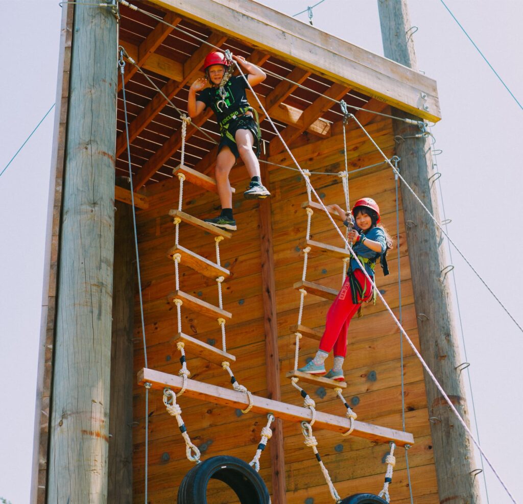 Kids climbing up the vertical playground at a large family gathering.