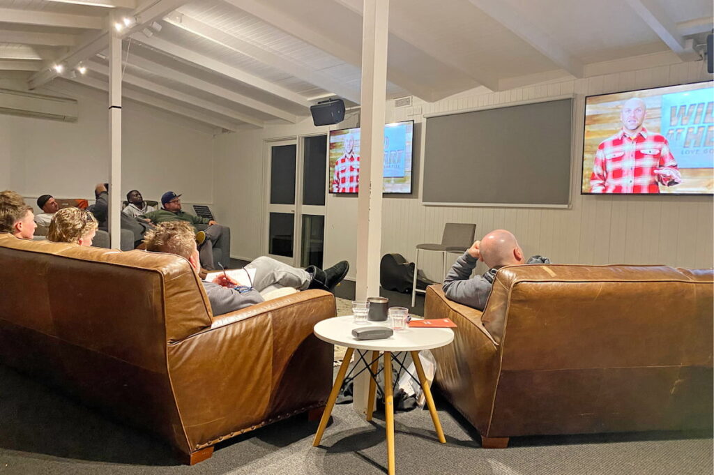 Picture of large group on couches in the camp retreat conference room enjoying accommodation and training retreat.