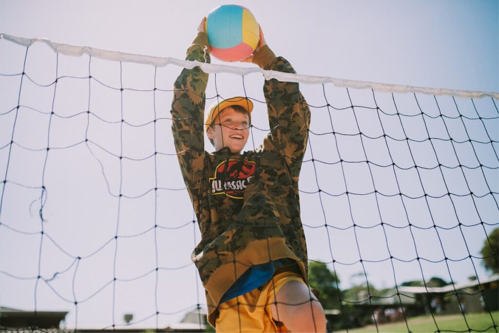 Teen playing volleyball. Looking up at the top of the net on family retreat at Golden Valleys.