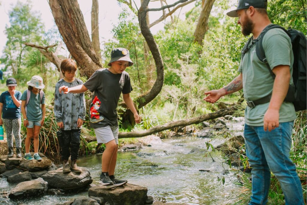 Image of church camp with youth crossing a creek to hike the National Park.